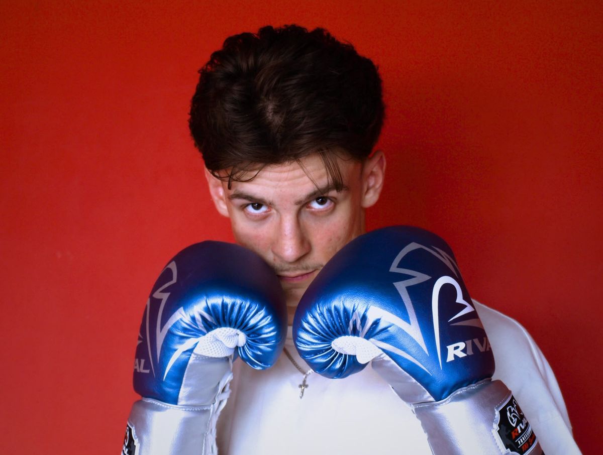Jakub Siedliski w rękawicach bokserskich na czerwonym tle